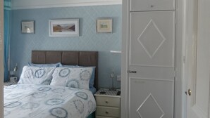 Une chambre à coucher comprenant un lit, une table de chevet, une commode et une armoire.