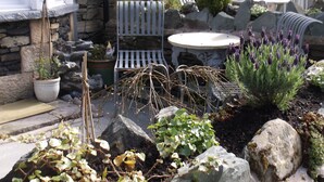 Une maison en pierre dotée d’un patio avec mobilier d’extérieur, des plantes en pot et un mur en pierre.