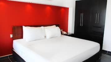 A hotel room with a large bed, red walls, and a black wardrobe.