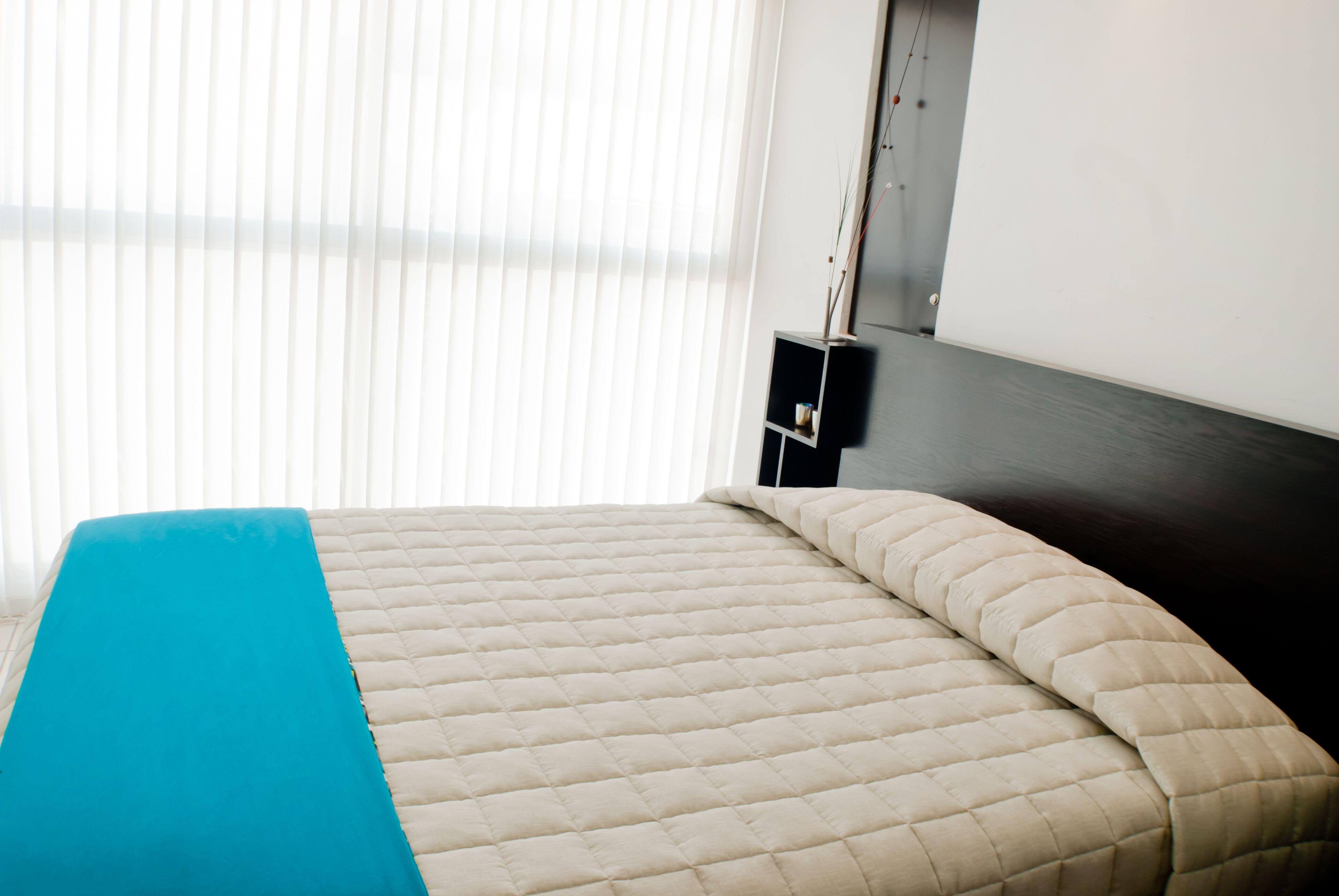 Una habitación de hotel con una cama, un edredón azul y una ventana con persianas.