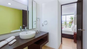 A modern bathroom with a large mirror, a white sink, and a dark wooden vanity.