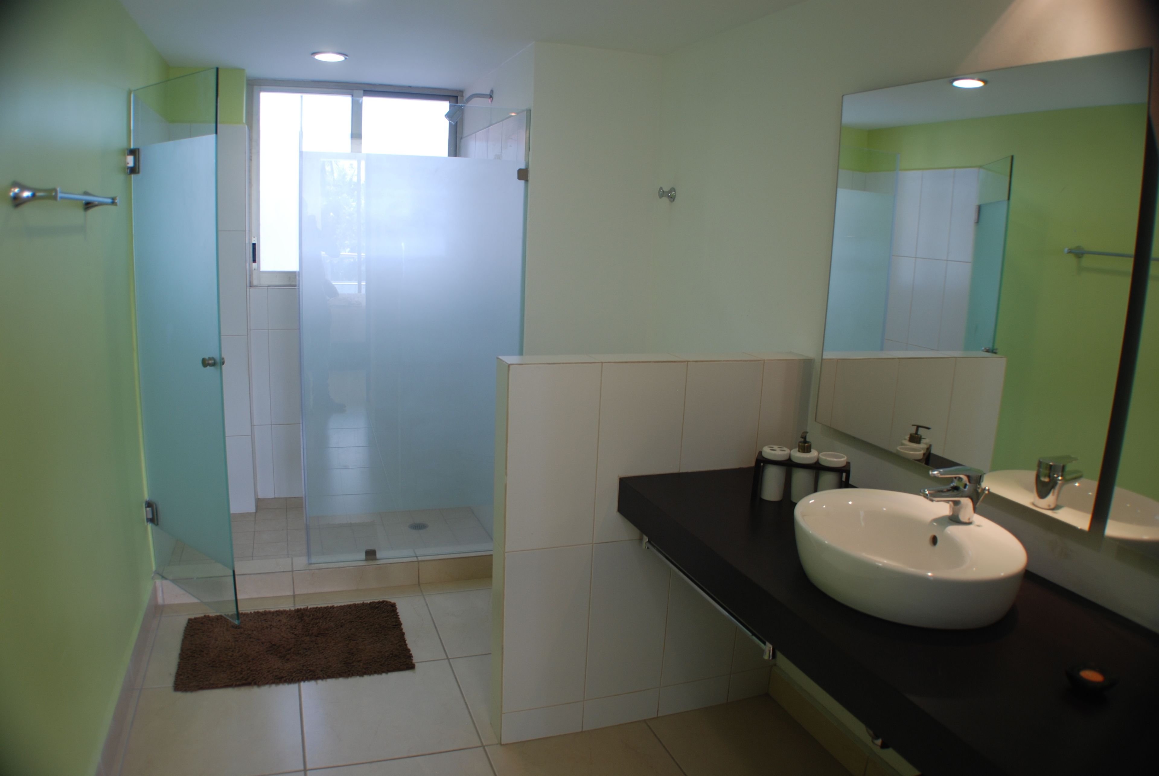 A modern bathroom with a glass shower enclosure, a white sink, and a large mirror.