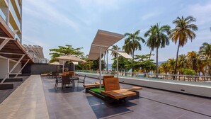 An outdoor seating area with tables and chairs, a wooden bench, and a canopy.