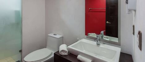 A modern bathroom with a white toilet, a sink with a mirror, and a glass shower enclosure.
