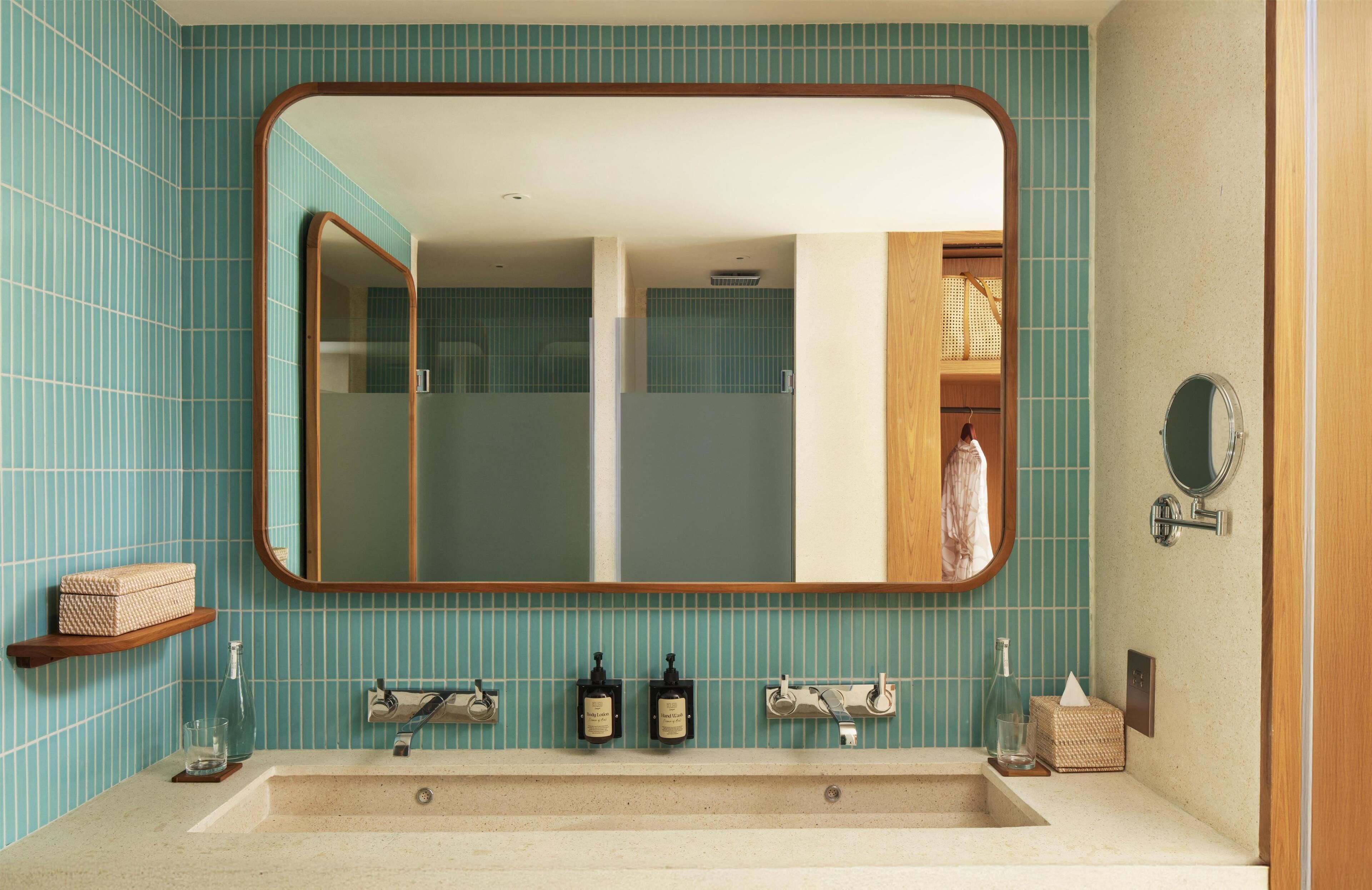 A bathroom with a large mirror, two sinks, and a towel rack.