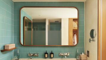 A bathroom with a large mirror, two sinks, and a towel rack.