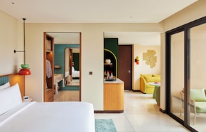 A hotel room with a bed, a desk, a sofa, and a bathroom visible through an open door.