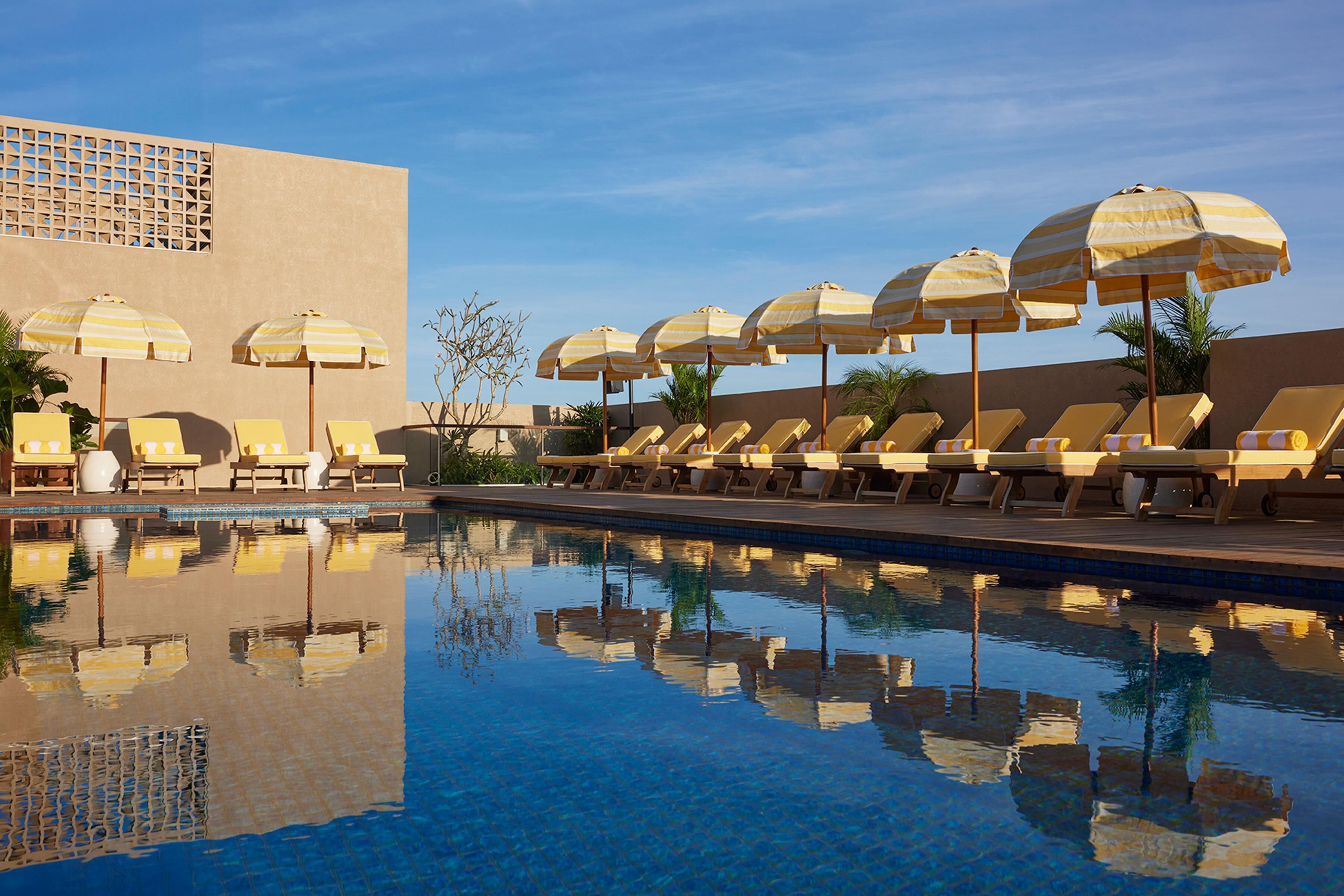 Una piscina al aire libre, sombrillas, tumbonas