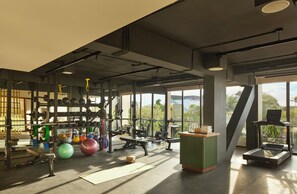 A gym with various exercise equipment, large windows, and a view of the outdoors.