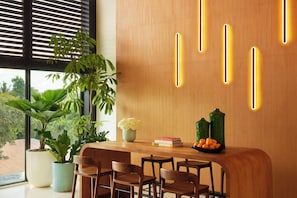 A modern interior with a wooden reception desk, potted plants, and a view through the window.