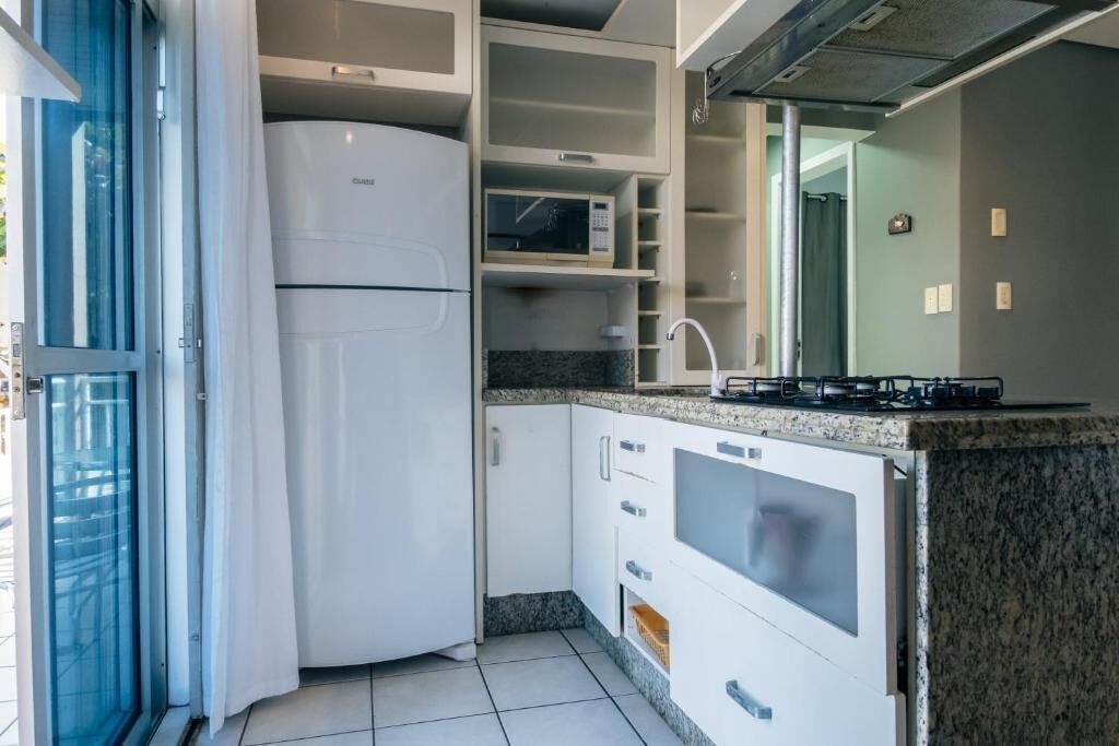 A compact kitchen with a built-in refrigerator, microwave, and gas stove.