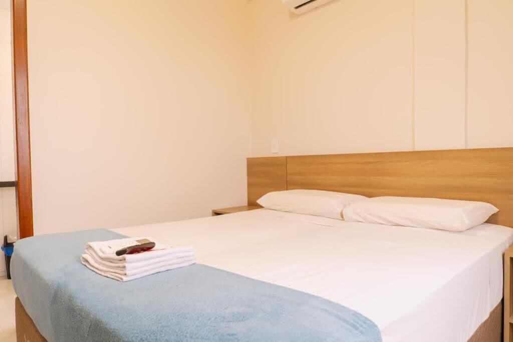 A hotel room with a single bed, a wooden headboard, and a blue blanket.