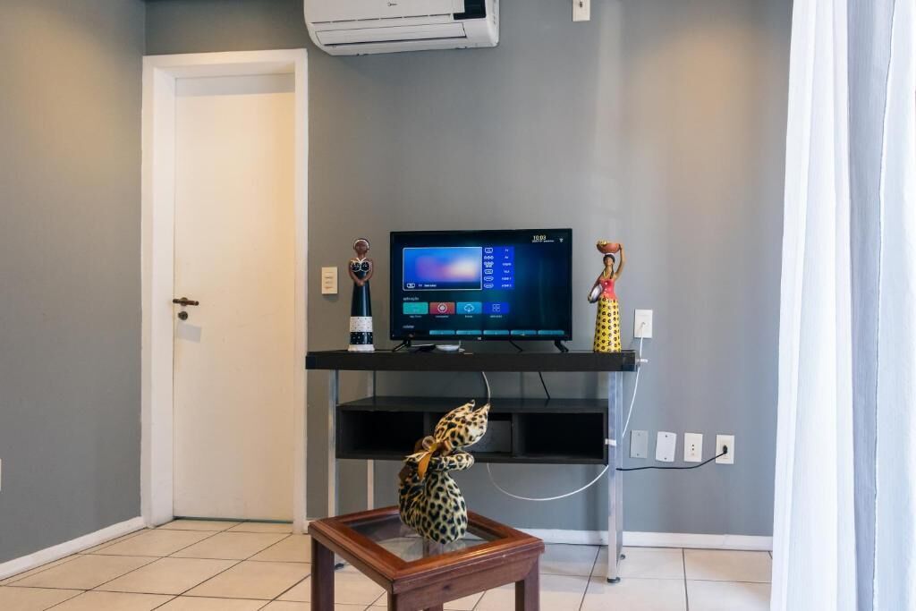 Ein Zimmer mit einem Fernseher auf einem Schrank, einem kleinen Tisch mit einer Leopardenfigur und einer Tür.