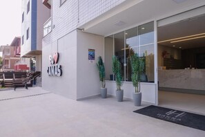 A hotel entrance with a reception desk, potted plants, and a clear view of the interior. - HANNA Amsterdam Hotel (Florianópolis)