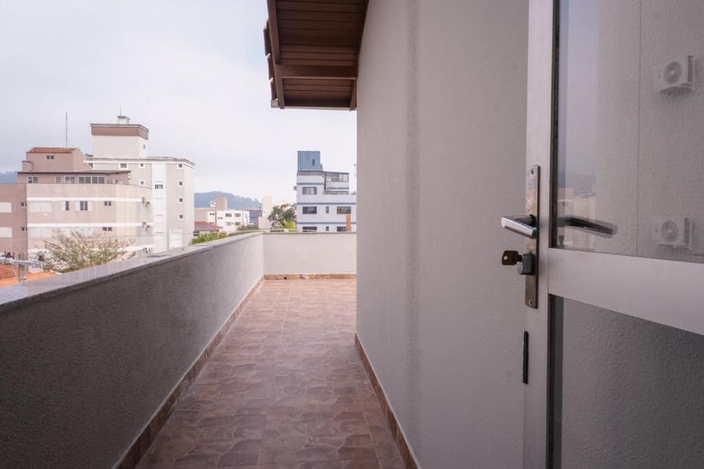 A narrow corridor with a tiled floor leading to a door with a metal handle.