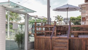 A wooden deck with a glass enclosure, outdoor seating, and a staircase leading to a higher level. - HANNA Amsterdam Hotel & Events (Florianópolis)