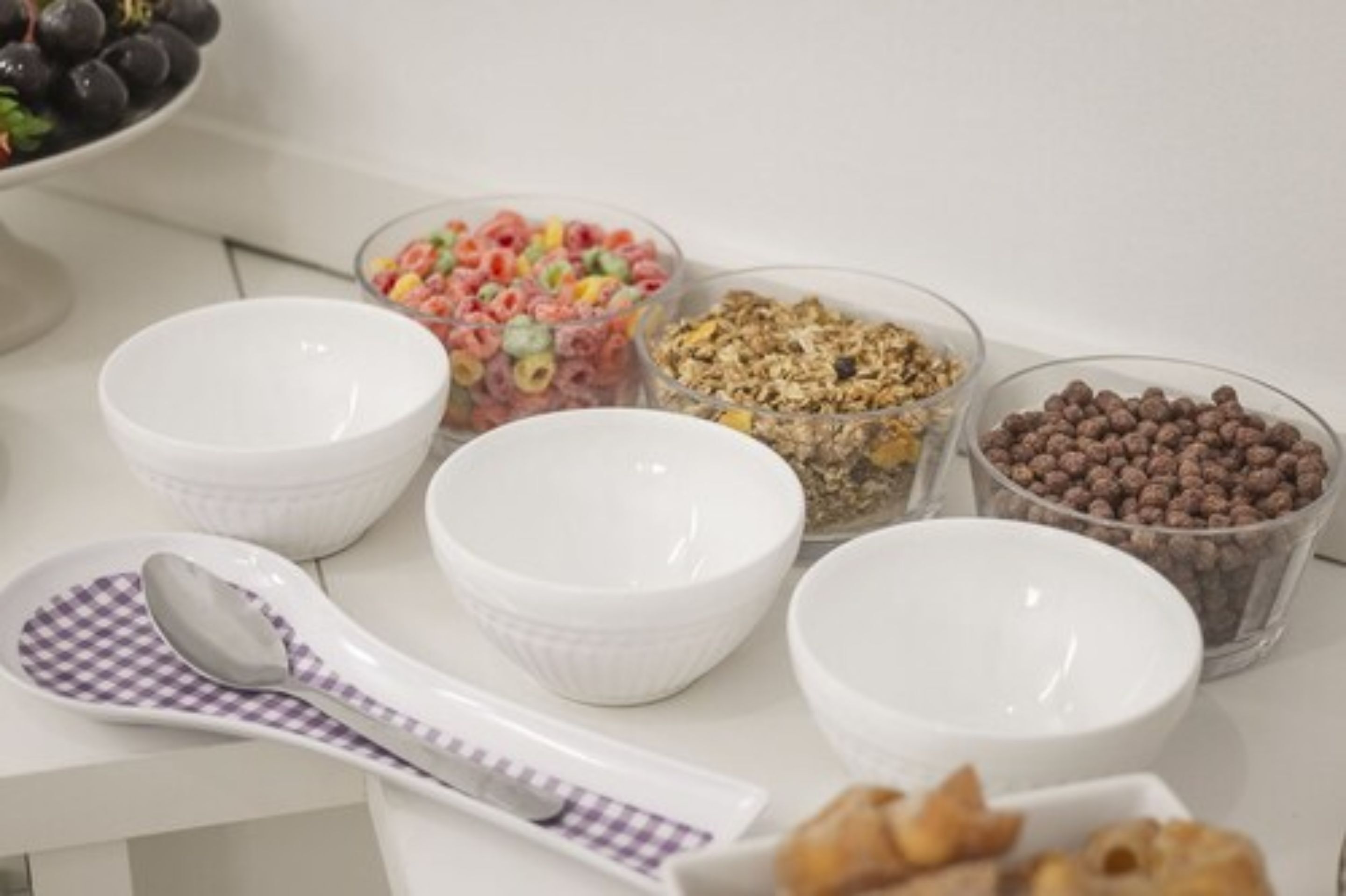 En morgenmadsbuffet med forskellige typer cornflakes og en ske på en ternet serviet.