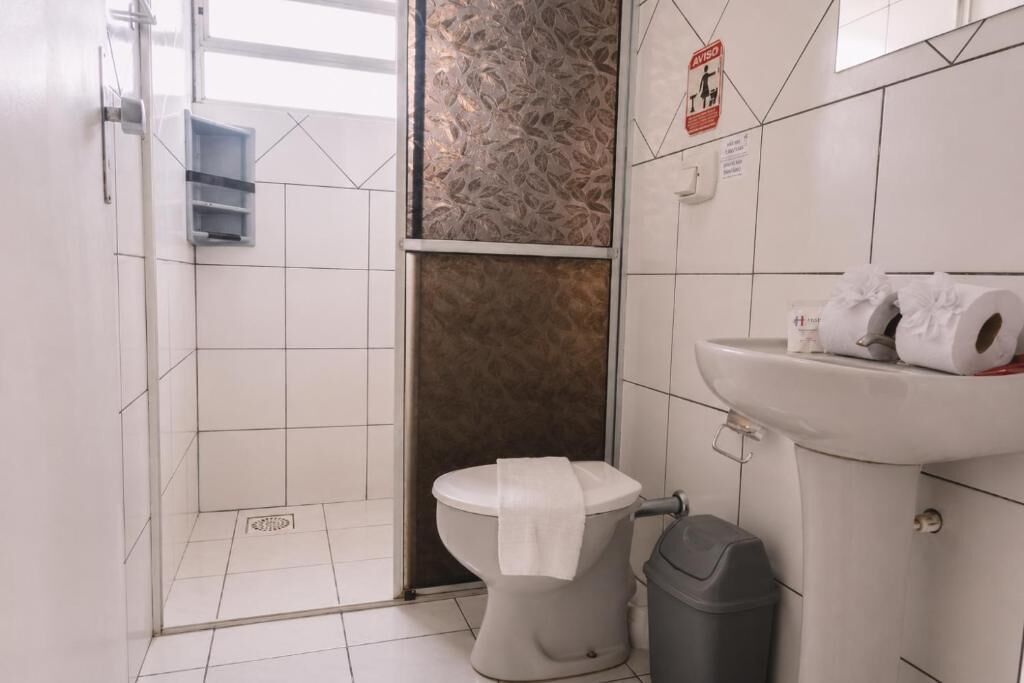 Baño con inodoro, lavamanos y cubo de basura.