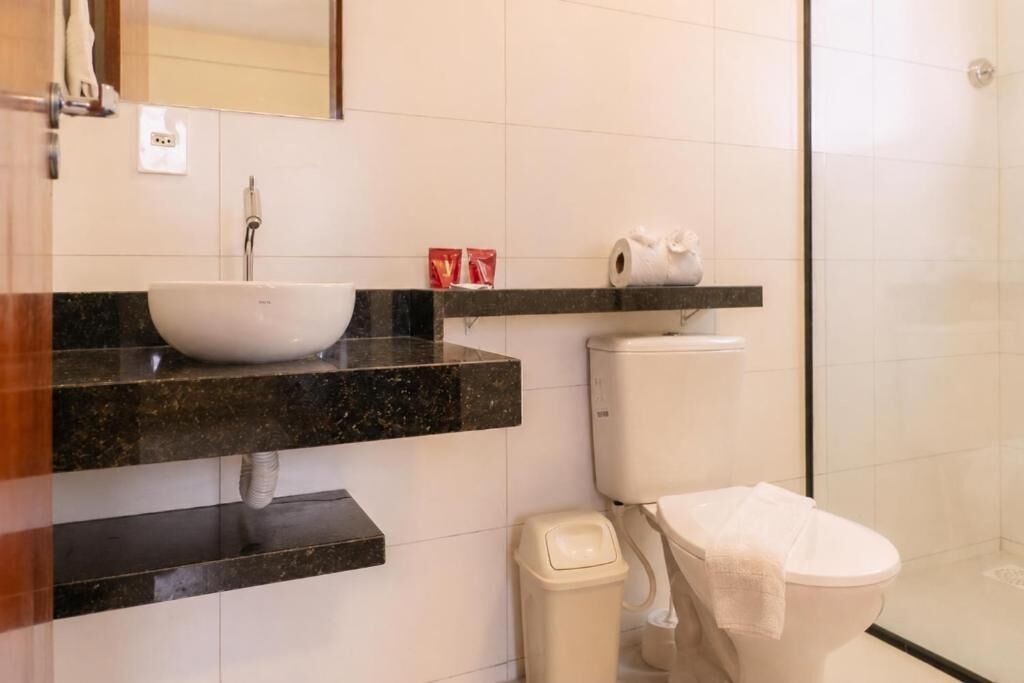 Casa de banho com lavatório branco, sanita e cabine de duche.