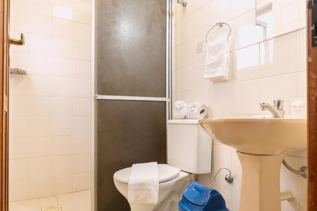 Une salle de bain comprenant des toilettes, un lavabo et un espace douche.