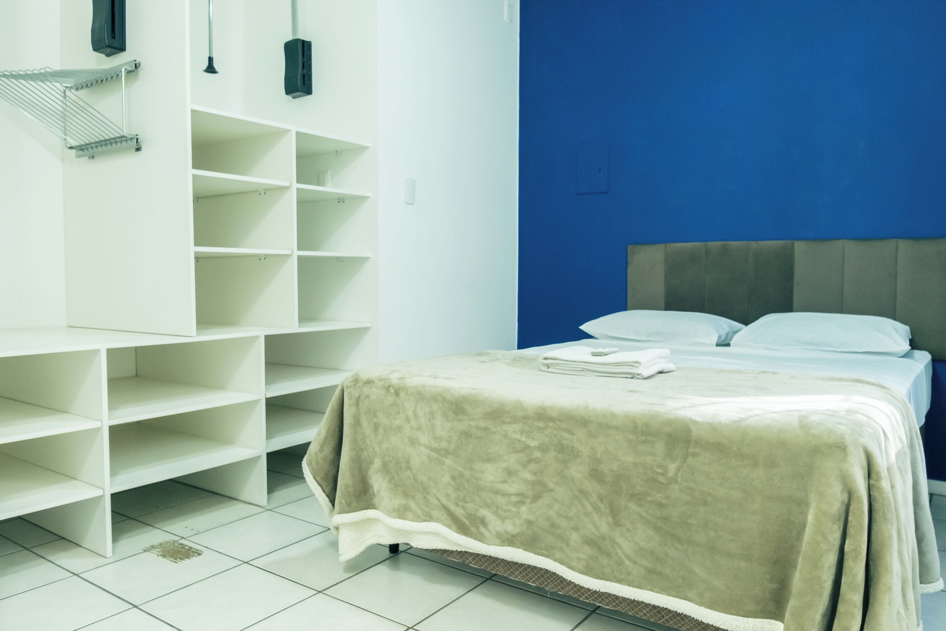 Ein Hotelzimmer mit einem Bett, einer blauen Akzentwand und einem weißen Regalelement.