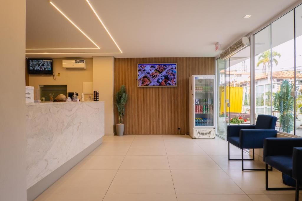A reception area with a marble counter, a television mounted on the wall, a vending machine, and seating area with chairs.