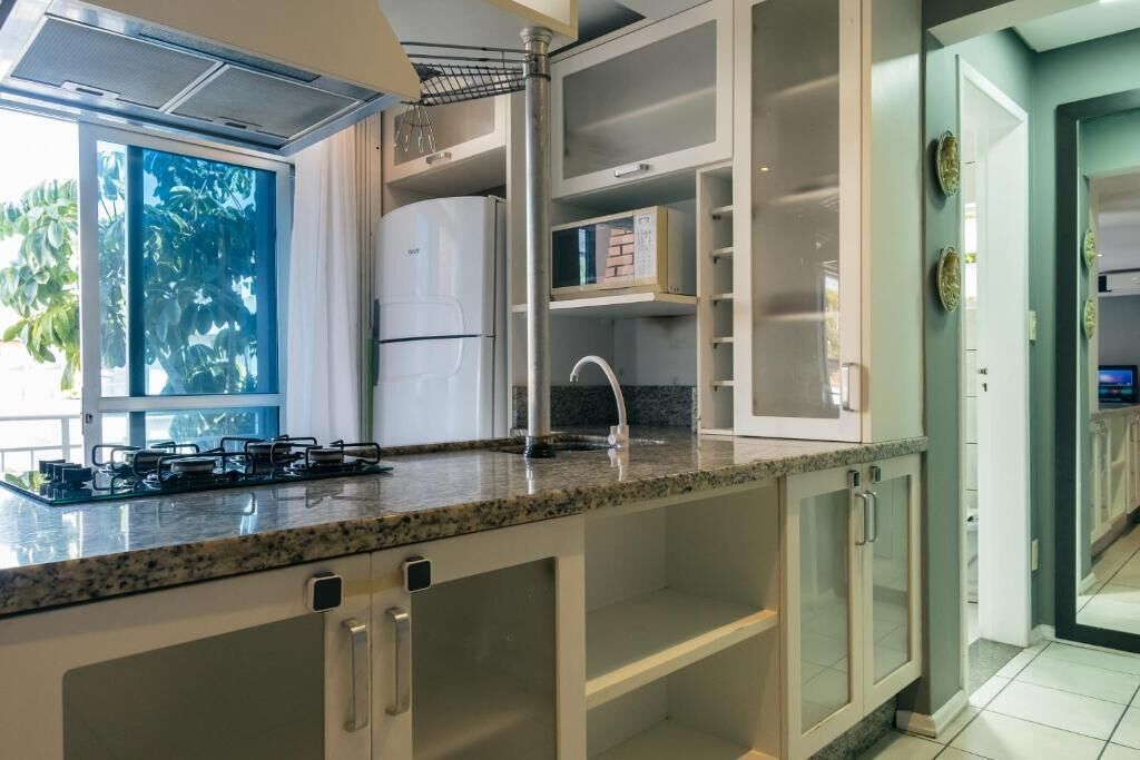 A kitchen with a built-in gas stove, a stainless steel refrigerator, and a window with a view of greenery.