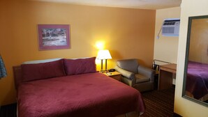 Ein Hotelzimmer mit einem großen Bett, einem Sessel, einem Schreibtisch und einem Spiegel.