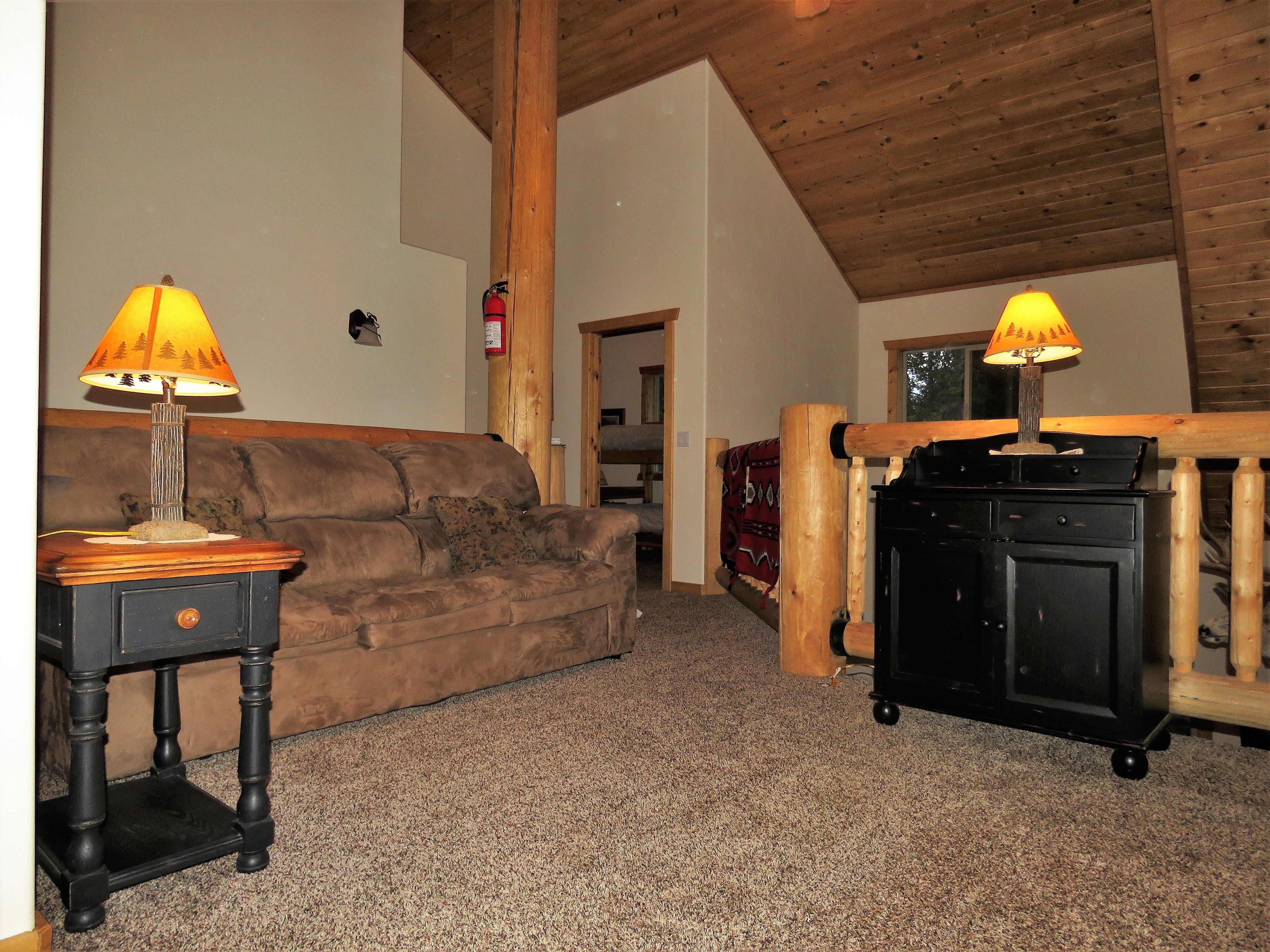 A cozy living room with a brown sofa, two lamps, and a black cabinet.