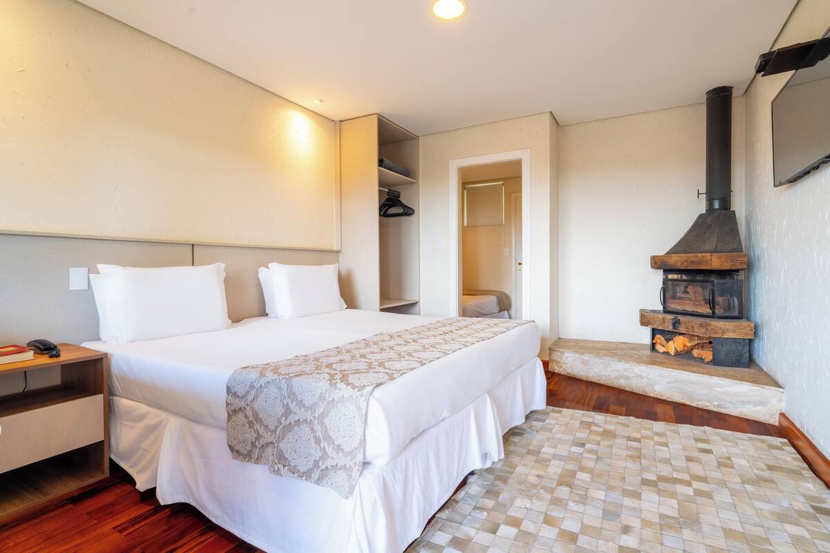 Une chambre à coucher comprenant un lit, une table de chevet et un poêle à bois encastré.