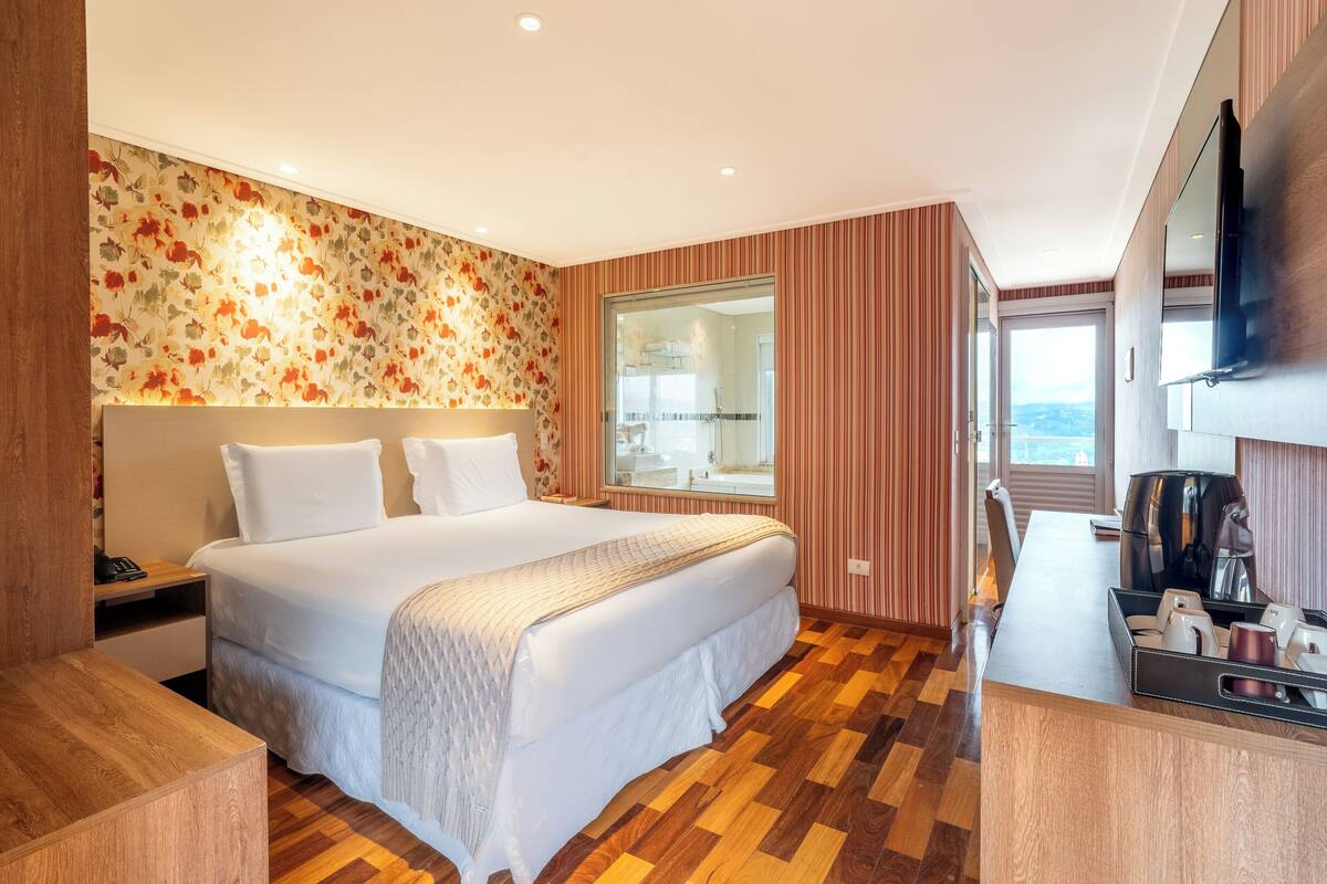 Une chambre d’hôtel avec un grand lit, un bureau équipé d’une machine à café et une vue sur la ville.