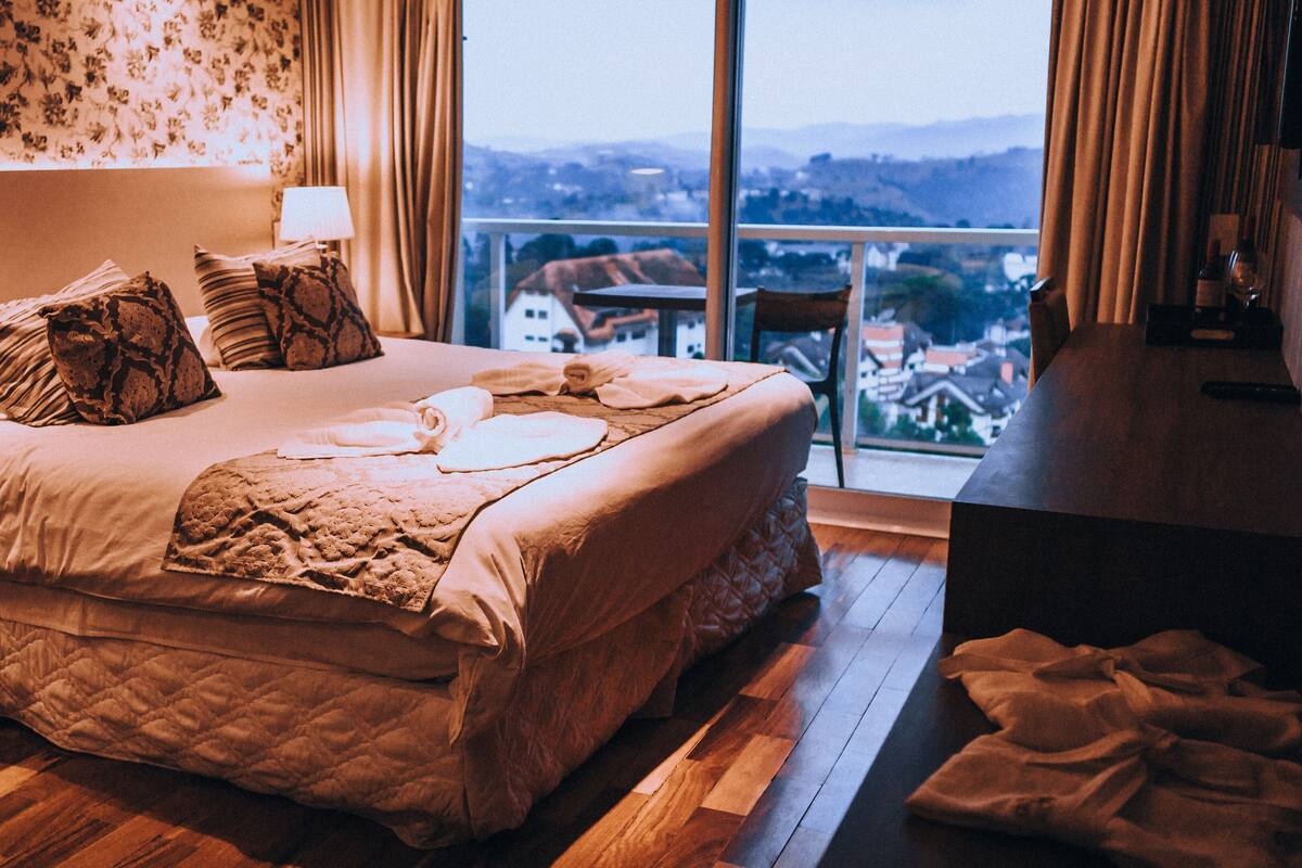 Une chambre avec un grand lit, une vue sur la ville par la fenêtre et un balcon.