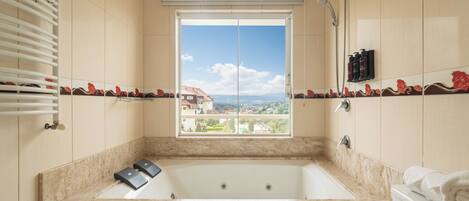 Ein Badezimmer mit einer großen Badewanne, einem Fenster mit Blick auf Gebäude und einem Handtuchhalter.
