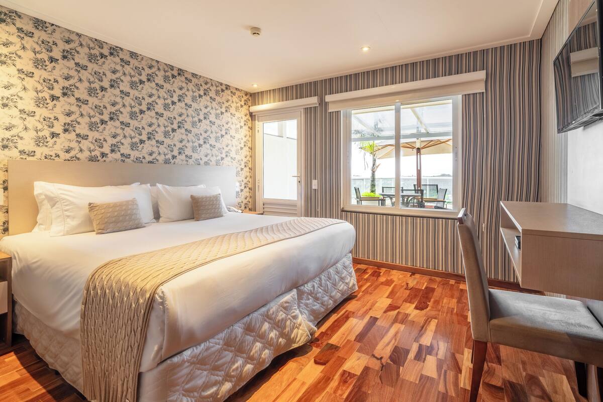 Une chambre d’hôtel avec un grand lit, un bureau et une fenêtre donnant sur l’extérieur.