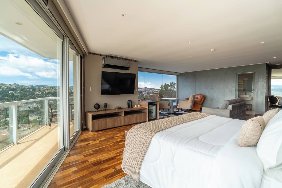 Une chambre moderne avec un grand lit, une télévision et un balcon offrant une vue sur la ville.