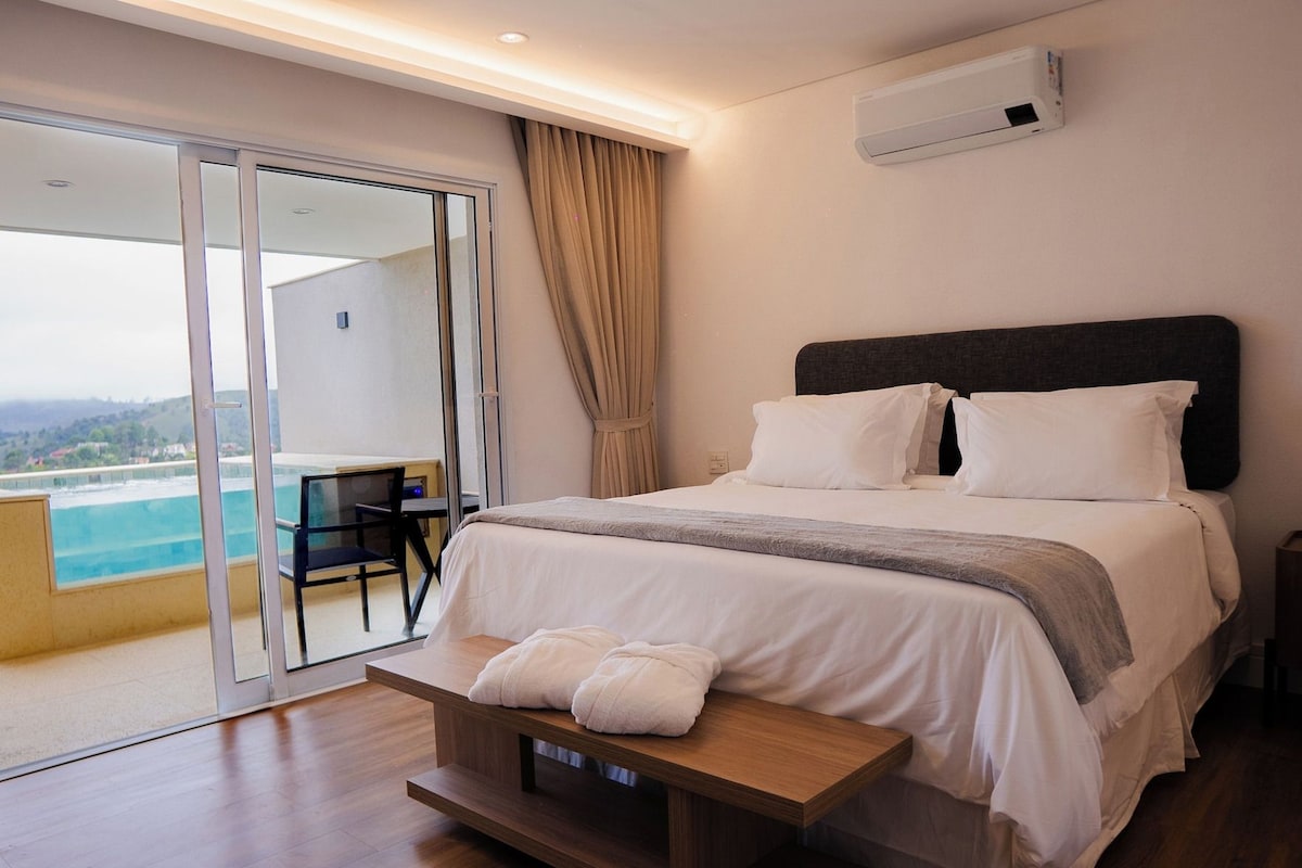 A hotel room with a bed, a desk, and a view of the ocean.