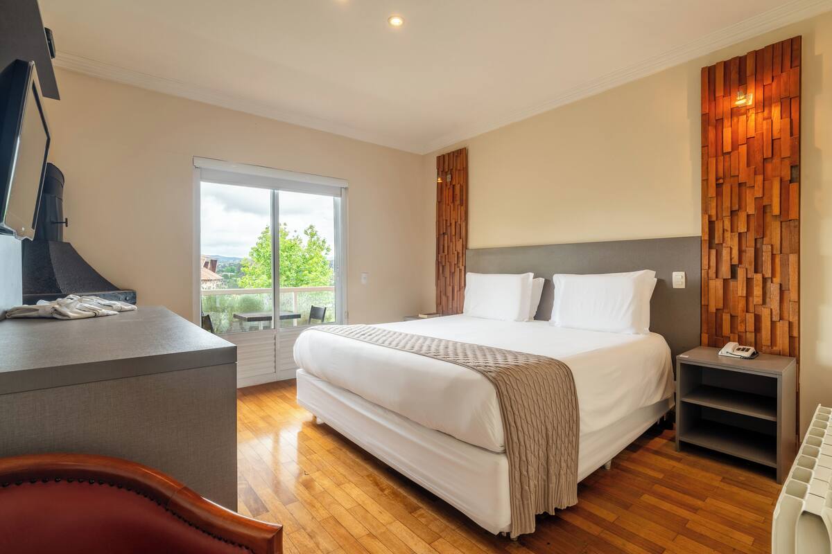 Une chambre d’hôtel moderne dotée d’un grand lit, d’un bureau et offrant une vue sur l’extérieur.