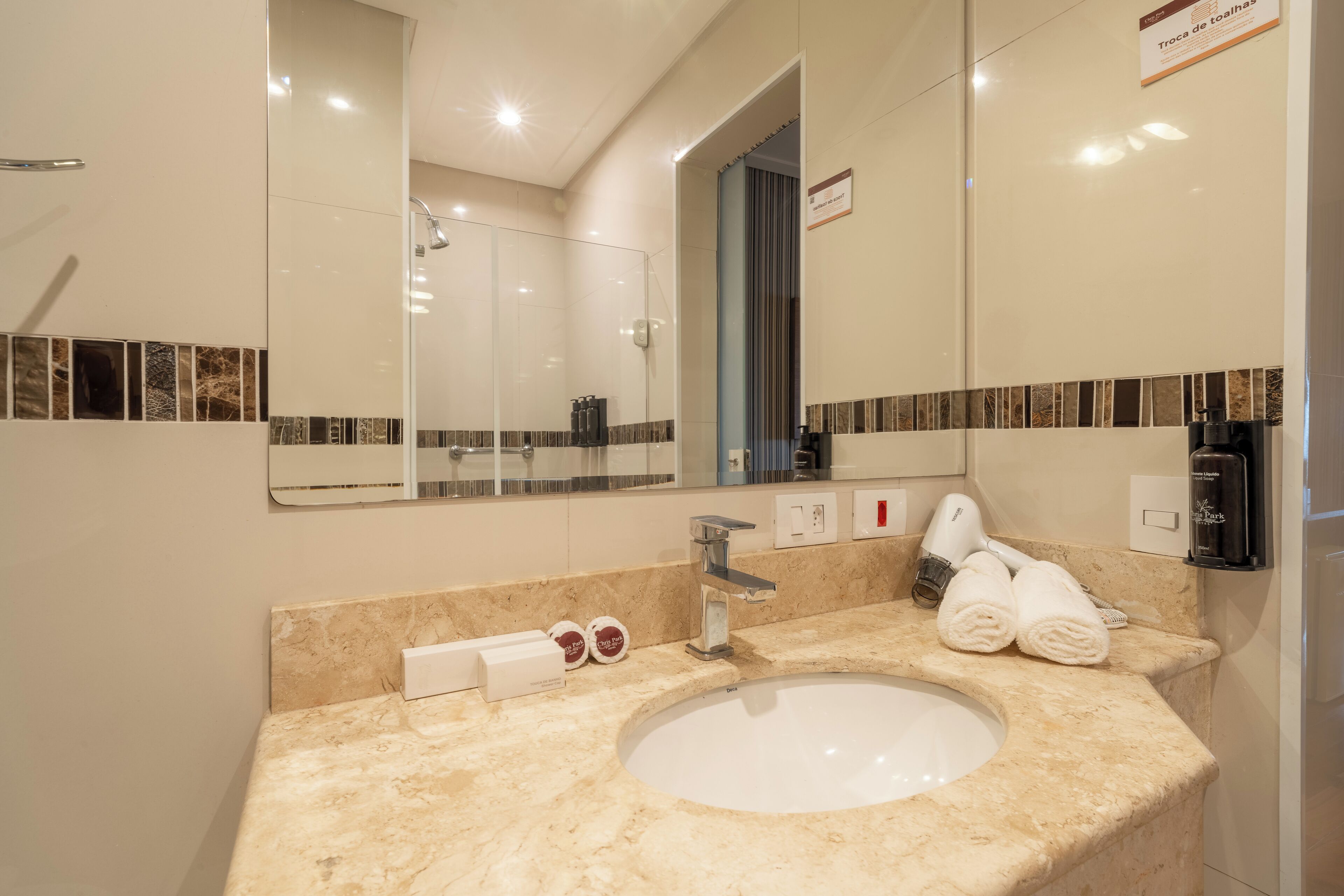 A modern bathroom with a large mirror, a sink, and a shower.