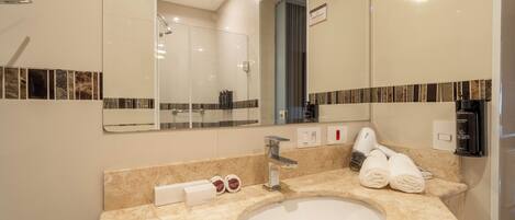 A modern bathroom with a large mirror, a sink, and a shower.