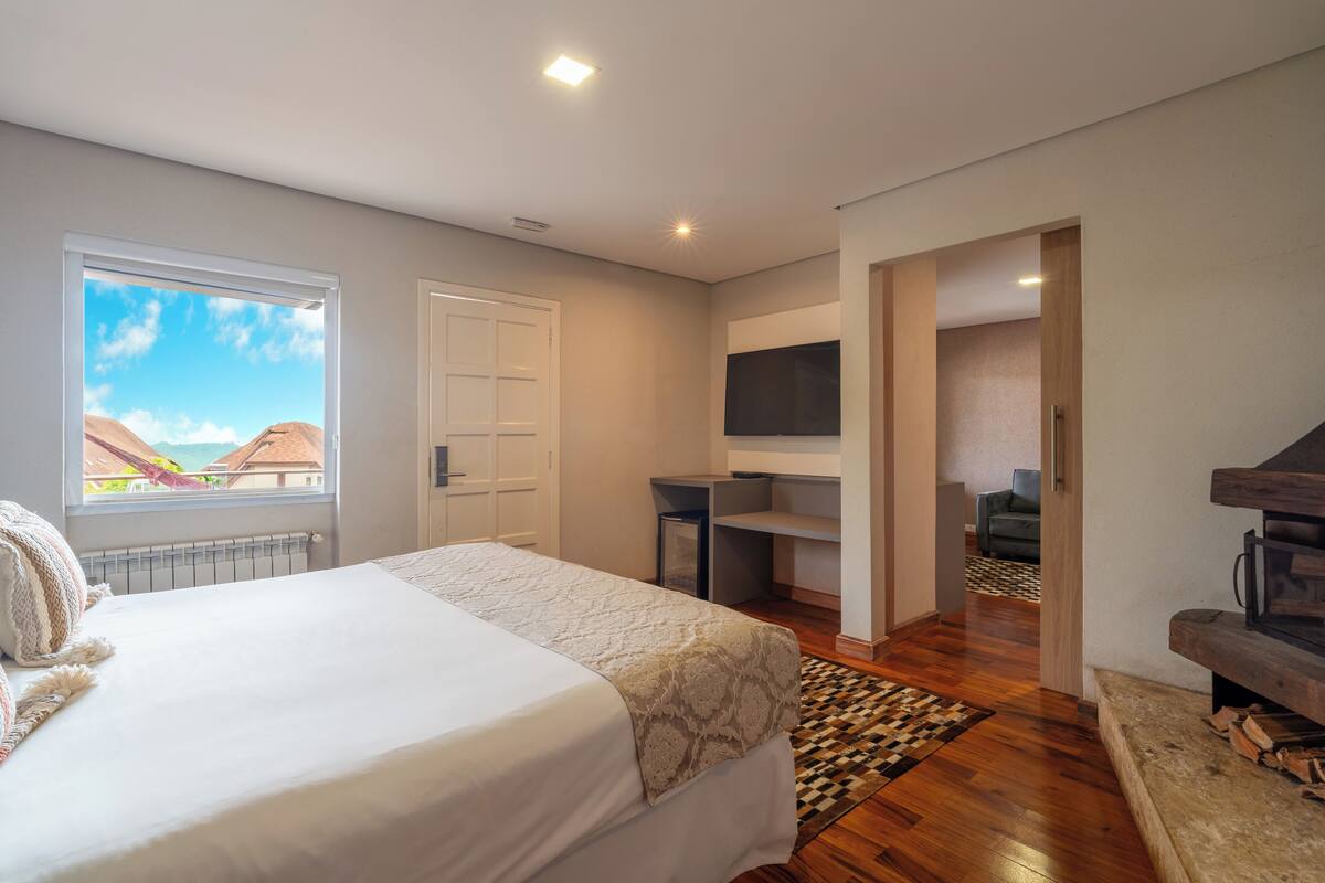 Une chambre à coucher avec un lit, un bureau, une télévision et une vue sur l’extérieur.