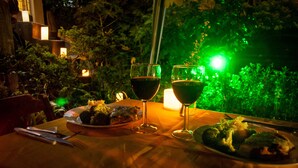 A table set for dinner with plates of food, two wine glasses, and a candle. - Pousada Estrelas da Babilonia (Rio de Janeiro)