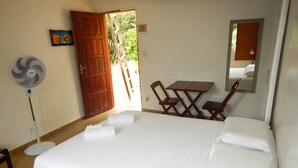 A hotel room with a bed, a desk, two chairs, a fan, and a door leading outside. - Pousada Estrelas da Babilonia (Rio de Janeiro)