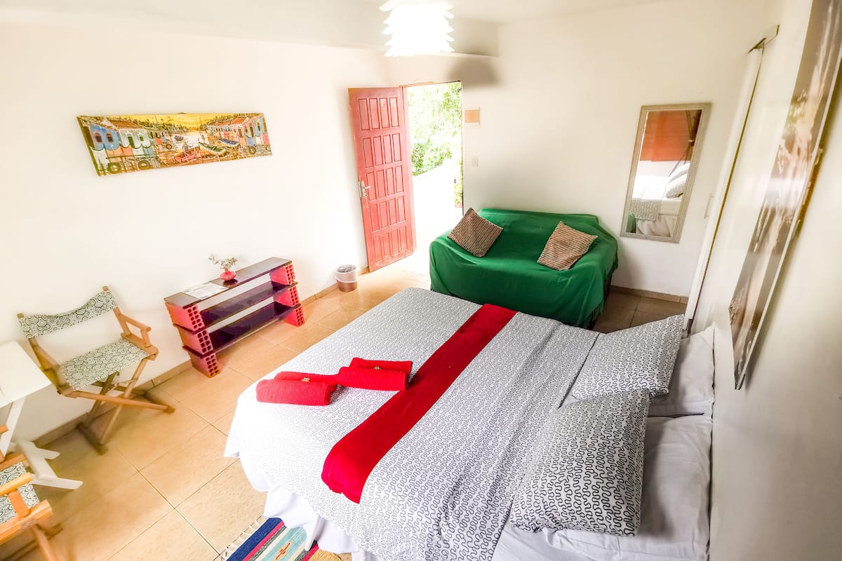 Une chambre à coucher avec un lit, un canapé vert, un bureau et une chaise.