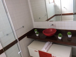 A bathroom with a glass shower enclosure, white tiled walls, a red basin, and small potted plants on the countertop. - Solar De Pipa Duplex Flat (Tibau do Sul)