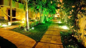 A pathway flanked by palm trees and greenery, leading to a building with a brick facade. - Solar De Pipa Duplex Flat (Tibau do Sul)