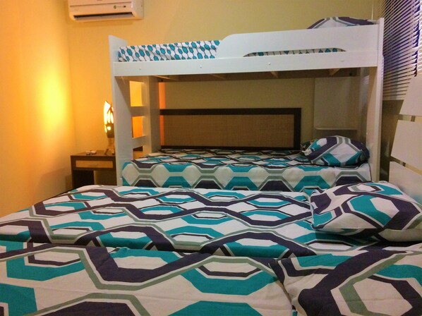 A bunk bed room with patterned bedding and a bedside table.