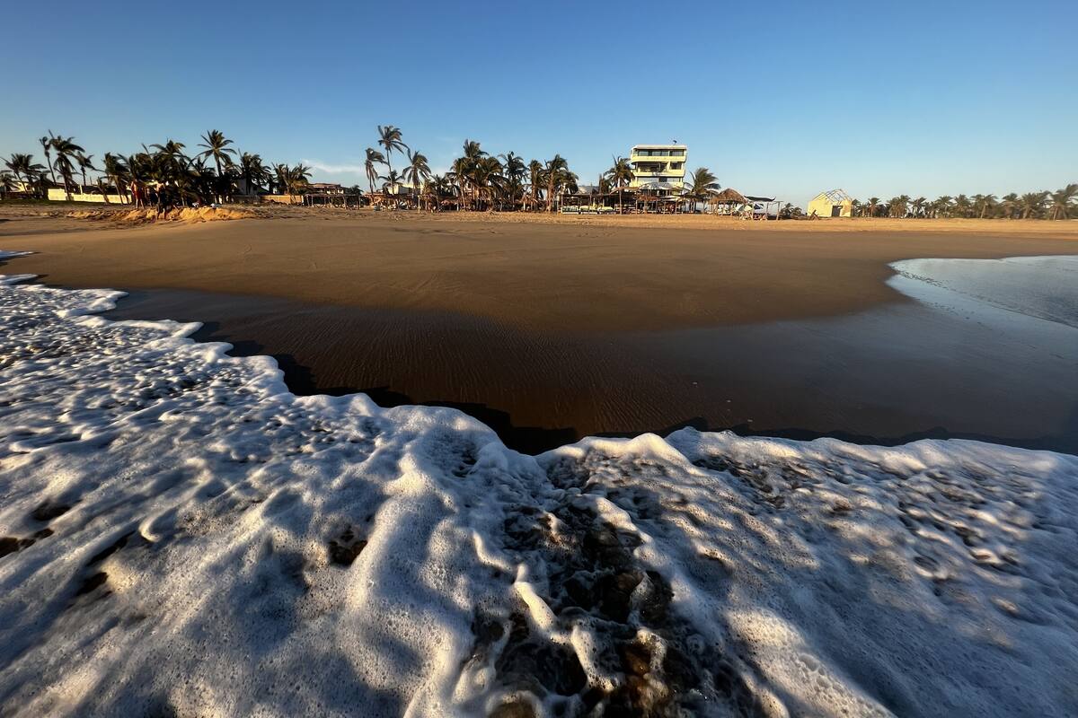 Una playa con un edificio al fondo.