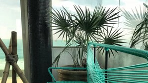 A green hammock chair with a view of the ocean through large windows.