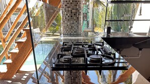 A modern kitchen with a gas stove, wooden flooring, and a view of the outdoors.
