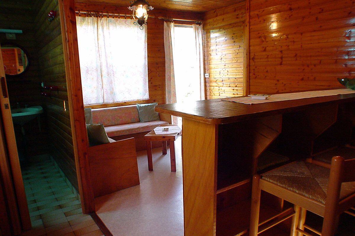 A wooden cabin interior with a wooden bench, a small table, and a bar area.